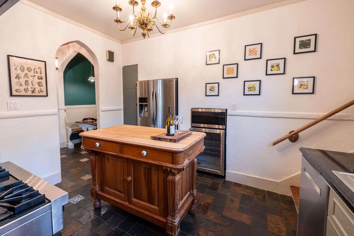 A welcoming kitchen scene with a striking kitchen island, elegant chandelier, framed artwork, and high-end stainless steel appliances. The layout invites both cooking and entertaining, making it the hub for family and friends.