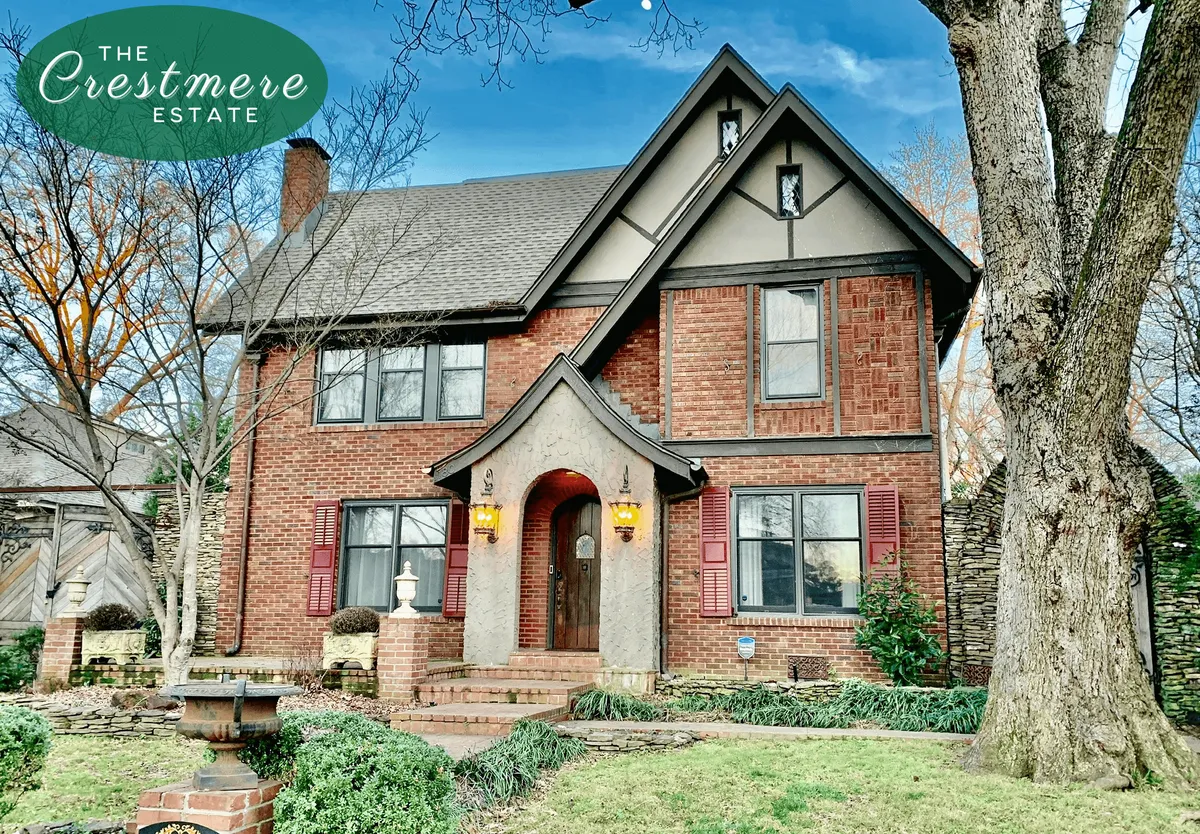 An inviting exterior shot of the estate’s brick facade, grand entrance, and lush landscaping beneath a large tree. The welcoming steps and windows evoke the charm and security of a family home.
